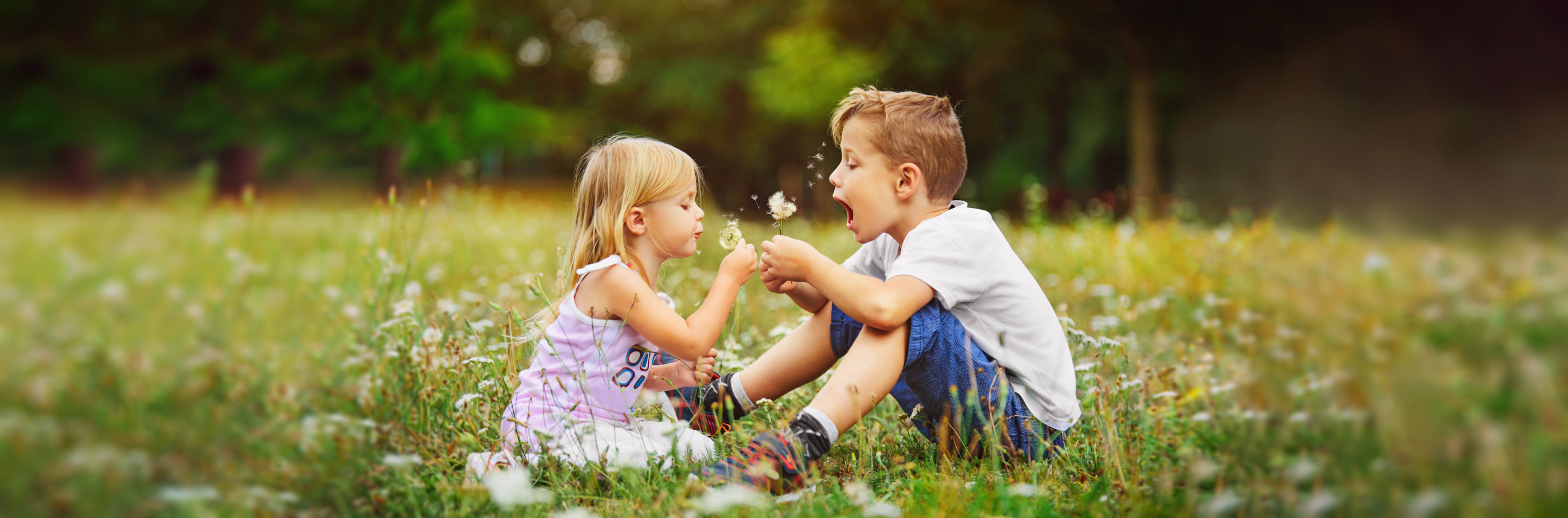 Zwei Kinder mit Pusteblume in der Natur, Kieferorthopädie an der Parkinsel, Ludwigshafen
